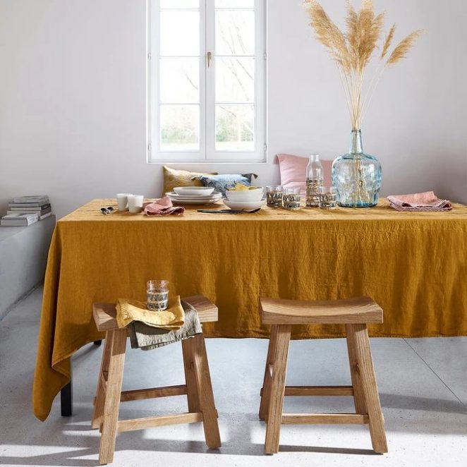 Bu yıkanmış keten masa örtüsü, doğal bir tarzda karşılama masası oluşturmak için koyu sarı bir renkle süslenmiştir.