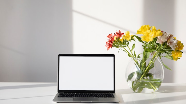 Vase mit Blumen in der Nähe des Computers